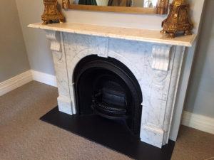 Victorian style arched custom made marble fireplace with a honed granite hearth